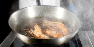 在煎锅上准备的油炸虎虾。厨师在锅里翻炒，搅拌，投掷，特写。慢动作的食物视频。给厨房。高清