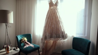 婚礼的一切都准备好了。豪华现代婚纱挂在窗口，婚礼花束在沙发椅子视频素材模板下载