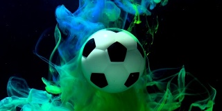 足球在一个惊人的背景。绿色和蓝色的墨水在水中在黑色的背景