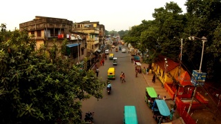 老加尔各答的夜晚街道，有汽车，行人，可以俯瞰摩托车，嘟嘟车，破旧的四层建筑，晾晒的衣服，绿树视频素材模板下载