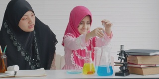年轻的穆斯林教师教她的学生在白色背景的房间里测试一些科学实验