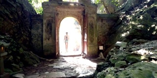 后视图女孩通过拱门离开老洞