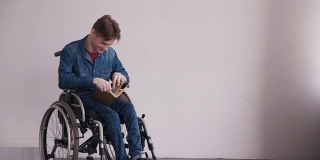 一个成年人坐在轮椅上，手里拿着书，坐在那里
