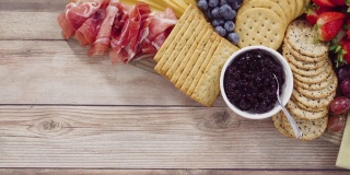 美味的奶酪、饼干和水果放在木板上切