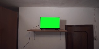 在一间又旧又黑的房间里有绿色屏幕的电视