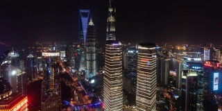 4k时间推移:陆家嘴金融区夜间空中俯瞰现代上海城市天际线，摩天大楼和交通灯的轨迹