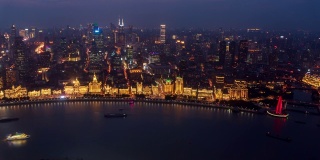 4k白天到夜晚的时间流逝:航拍上海城市全景外滩照明建筑和旅游渡轮在黄浦江，中国。