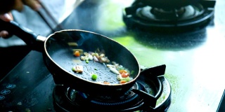 在咖啡馆里，炊具把蔬菜放在黑色的平底锅上做菜