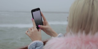 移动摄影。用智能手机拍摄海浪的女人