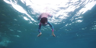 一个勇敢的小女孩独自在蓝色的深海里游泳和潜水。