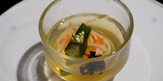 果冻布丁在透明杯中，玫瑰花瓣和金叶在桌上旋转。