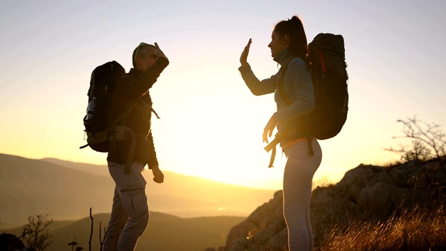 一对快乐的年轻夫妇正在收拾他们的背包去阿尔卑斯山徒步旅行。水瓶