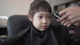 亚洲小女孩在理发店理发。手持拍摄，真实现场视频素材模板下载