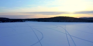 一个湖与雪地上的雪车痕迹的4K空中视频在日落，魁北克，加拿大