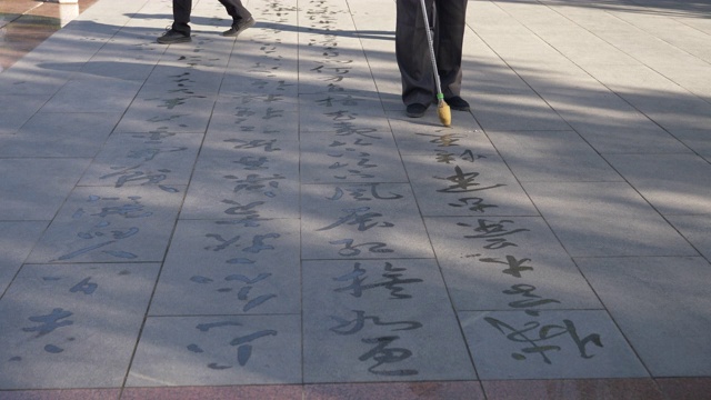 在中国甘肃张掖，人们用毛笔在地上书写佛经。