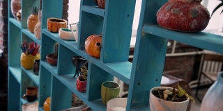 放着陶器、盘子和装饰花瓶的蓝色旧架子