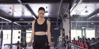女性在健身馆用重哑铃锻炼健康的生活方式，运动女性训练耐力强集中的二头肌锻炼。4K超高清影片，弧度拍摄