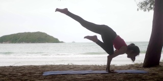 亚洲女人在海滩上的森林里练习瑜伽，健康积极的生活方式概念