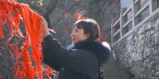 中国陕西庙里，女子在木棍上系红丝带。