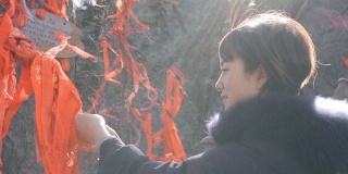 中国陕西庙里，女子在木棍上系红丝带。