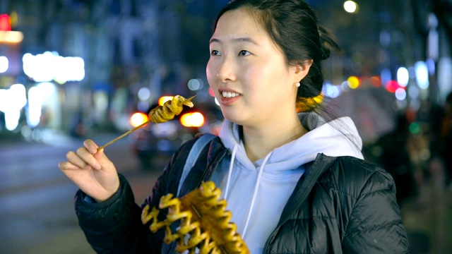 亚洲年轻女子喜欢街头小吃在晚上