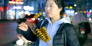 亚洲年轻女子喜欢街头小吃在晚上
