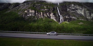 巨魔山瀑布和从火车窗口看到的汽车。挪威劳马铁路观光列车。