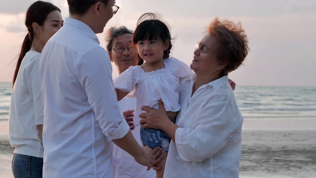 快乐的亚洲大家庭拥抱在日落的沙滩上的海浪。家庭，生活方式，人，人寿保险，多代人，老人，假期，关系，孩子，假期，退休，健康保健理念。