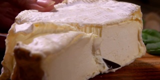 用刀切出带有白色霉菌的软山羊奶酪