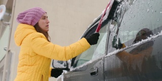 在雪地里开车。年轻女子在第一场雪后清理汽车。