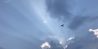 飞机飞越多云的太阳光束天空