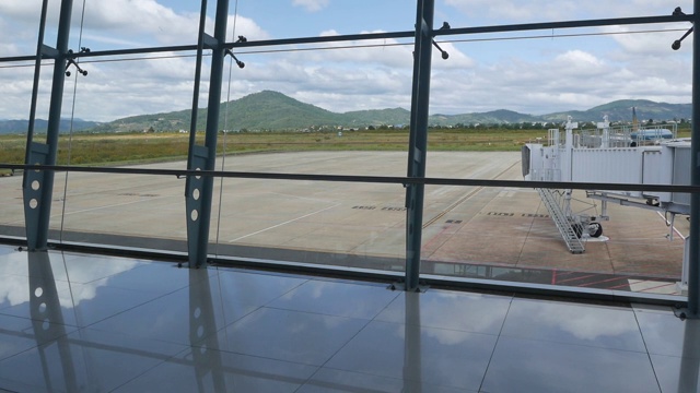 现代化的机场，通过窗口可以看到美丽的跑道和客运大楼。山的背景