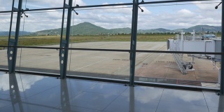 现代化的机场，通过窗口可以看到美丽的跑道和客运大楼。山的背景