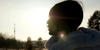 女人的剪影享受冬季的风景在背后的阳光
