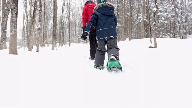 在暴风雪后的冬天，母亲和儿子在户外穿雪鞋