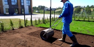 播后人工用压土机在院子内播撒草坪。万向节运动
