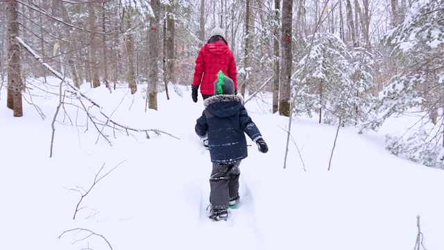 在暴风雪后的冬天，母亲和儿子在户外穿雪鞋