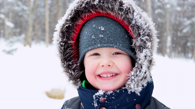 小男孩在冬天的暴风雨中在户外微笑。