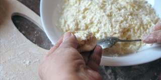 成熟女性的手在家里厨房用奶酪包饺子