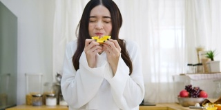 快乐的亚洲女人在厨房喝橙汁，健康的饮食和健康的概念。