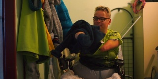 一个残疾人在公寓的走廊里脱下他的毛衣。