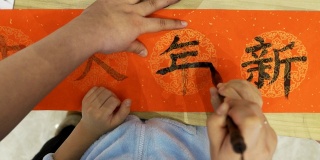 老师帮助孩子们用中国书法家写春联