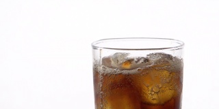 清凉的可乐倒进一个玻璃与冰在白色背景与文字空间。含咖啡因的冰饮料