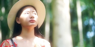 一位美丽的亚洲妇女戴着帽子环顾四周，阳光照在她的脸上