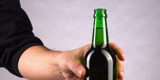 男人喝冰镇啤酒的背景。用手把冷藏的小麦或啤酒从架子上拿出来