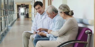 年轻的亚洲医生在医院里与年长的病人交谈