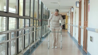 在走廊上用助行器走路的亚洲老妇人视频素材模板下载