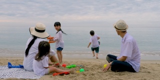 暑假一家人一起在沙滩上玩筑沙。家庭，假期和旅游的概念。