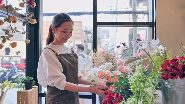 拥有花店的亚洲女人花店内准备出售，有专业的日本女人花店，花店在城市中，小的经营理念。