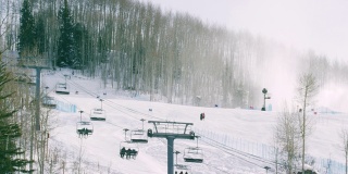 滑雪者和单板滑雪者乘坐滑雪缆车，人们在冬季科罗拉多山滑雪胜地的斜坡上滑雪(比弗溪)